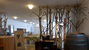 Una habitación con una mesa de madera, sillas, un barril grande y un letrero con caracteres japoneses.
