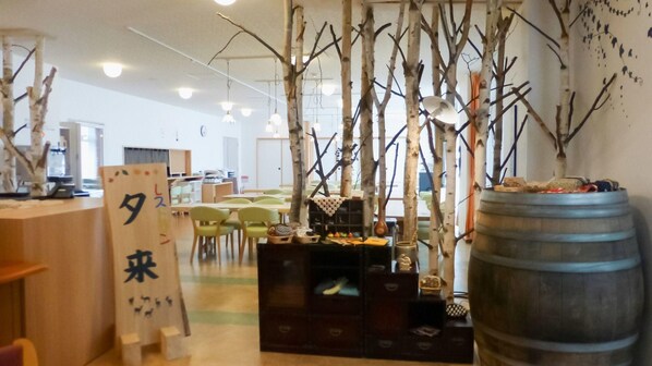A room with a wooden desk, chairs, a large barrel, and a decorative tree structure.