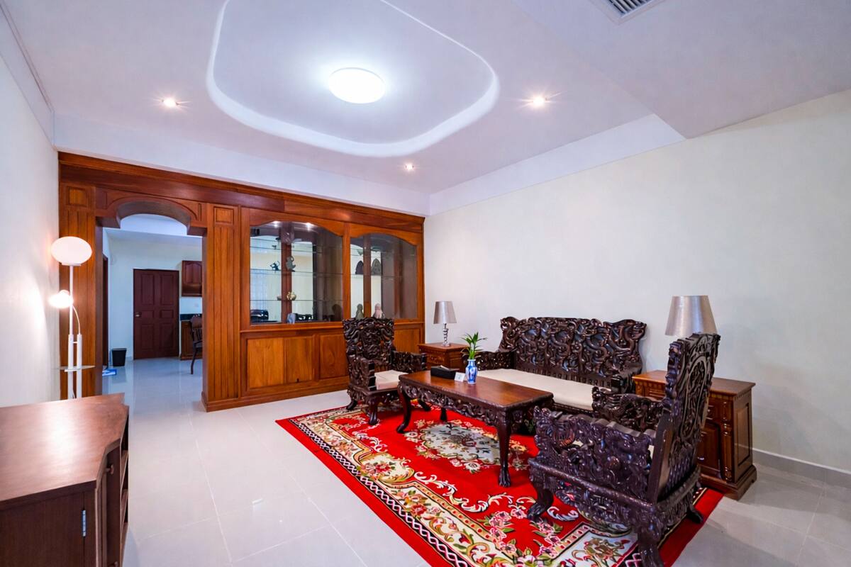 Une pièce comprenant une table à manger, des chaises, une moquette rouge, des meubles en bois et un luminaire au plafond.