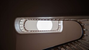 Vista di una scala con ringhiera e una finestra circolare nella parte superiore.