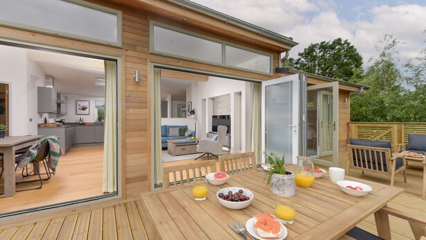 A wooden deck with a breakfast setup including a table, chairs, and a variety of breakfast items. - 5 Southern Place (Liskeard)