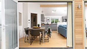 An open sliding door leading to a dining area with a table, chairs, and a bowl of fruit. - 5 Southern Place (Liskeard)