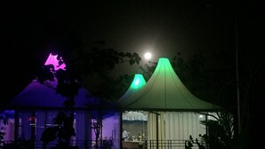 A tent with a green roof, a purple-lit room, and a moon in the background. - Jayshrea Meadows Tadoba Tiger Resort (Bhadravathi)