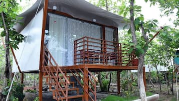 Una casa en un árbol con una escalera que lleva a un balcón.