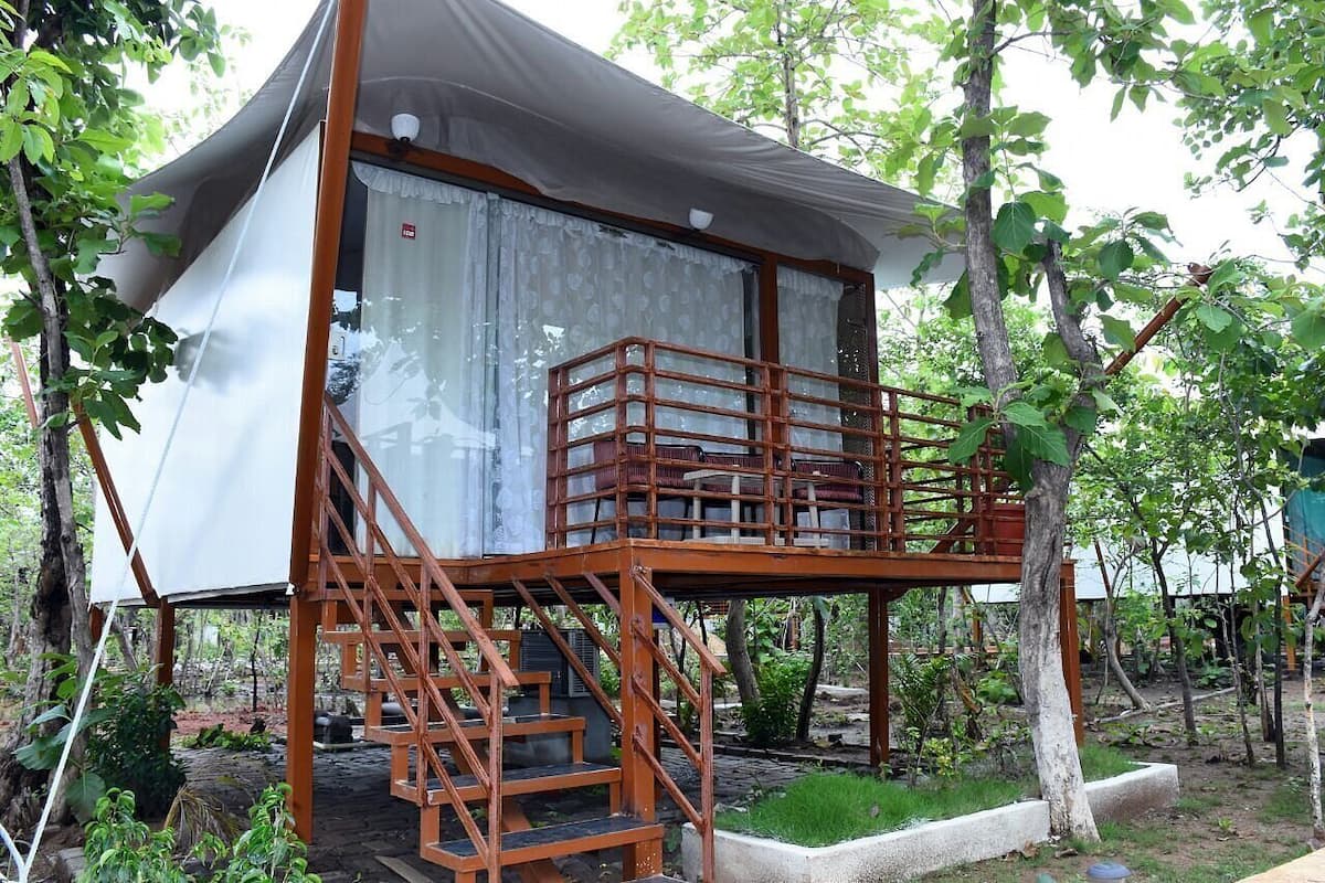 Uma casa na árvore com uma escada que dá para uma varanda.