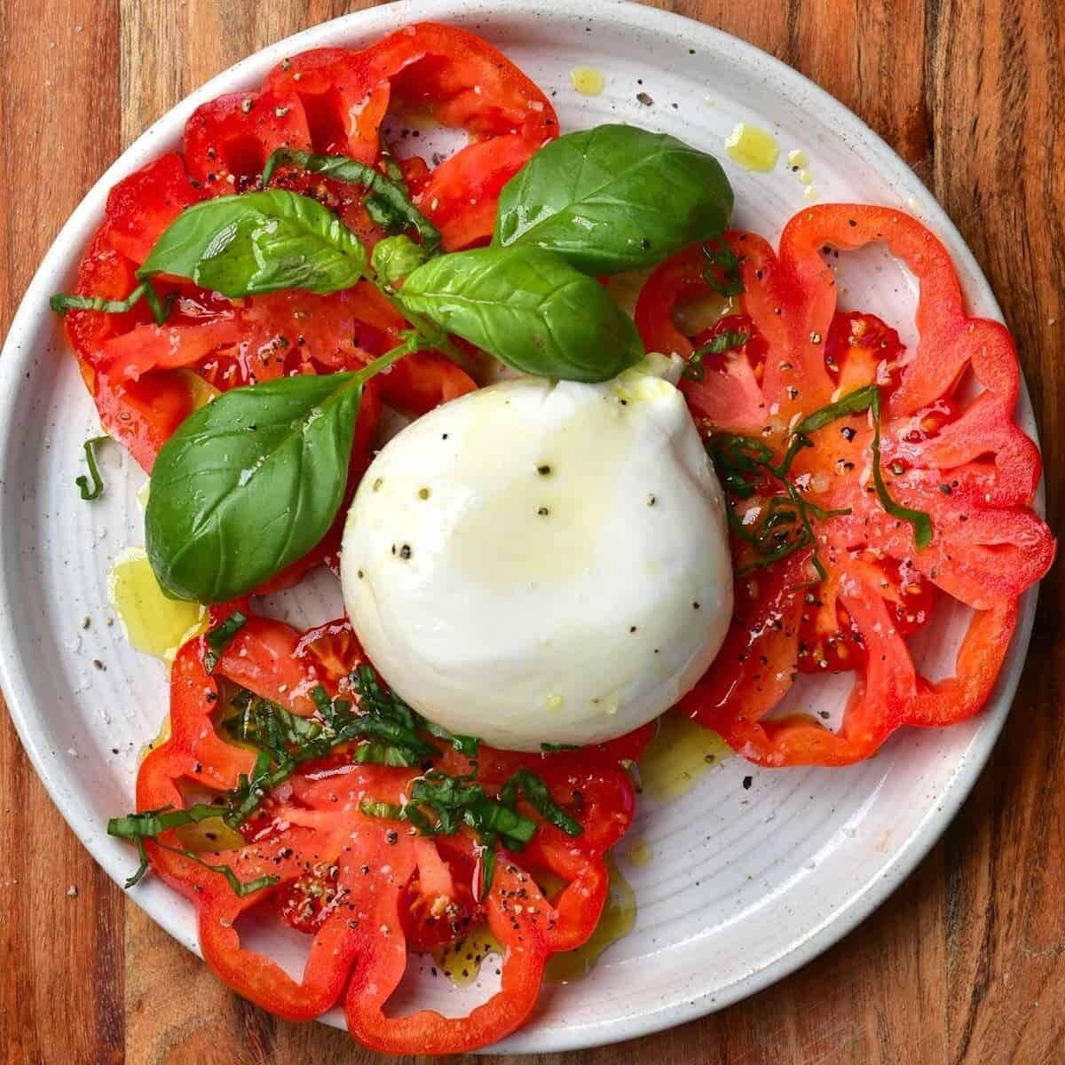 A plate of Caprese salad with tomatoes, mozzarella, and basil.