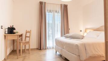 Ein Schlafzimmer mit Bett, Schreibtisch mit Stuhl und einem Vorhangfenster.
