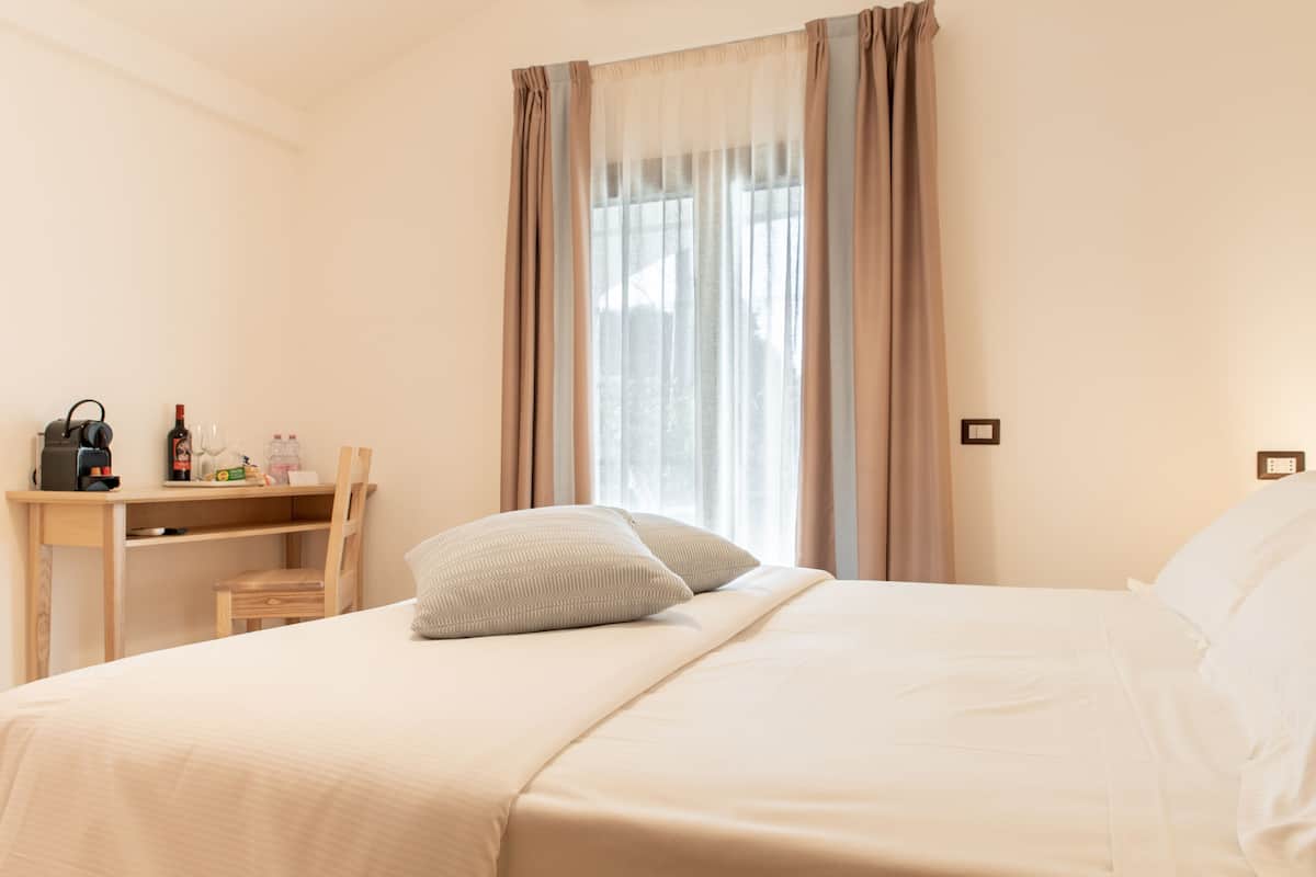 A hotel room with a bed, a desk, and a chair.
