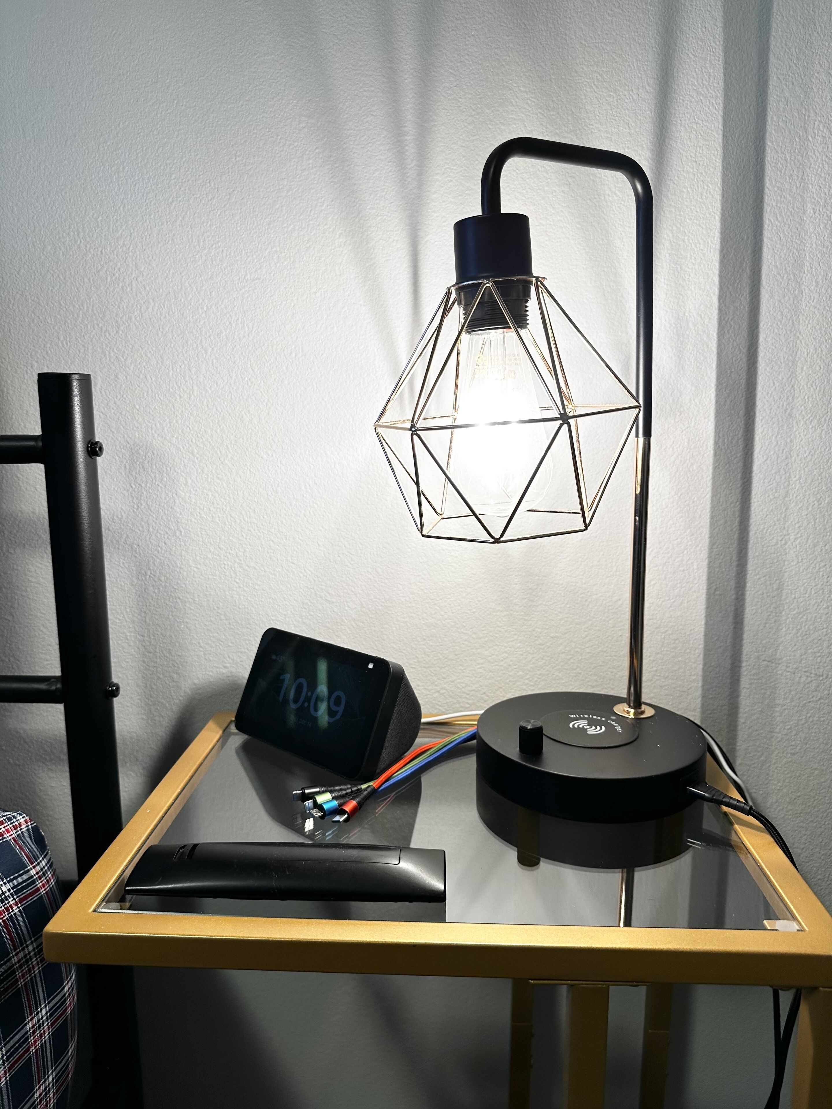 A desk with a lamp, a clock, and a power strip.
