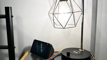 A desk with a lamp, a clock, and a power strip.