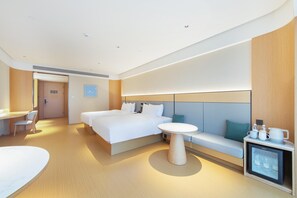 A modern hotel room with a large bed, a small round table, a sofa, a desk, and a mini-fridge. - Ji Hotel Xiangyang Dongjin Minfa Century Plaza (Xiangyang)
