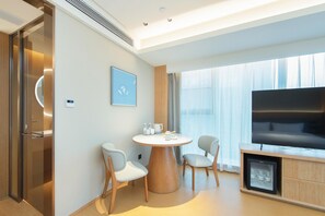 A modern hotel room with a round dining table, two chairs, a flat-screen TV, and a minibar. - Ji Hotel Xiangyang Dongjin Minfa Century Plaza (Xiangyang)