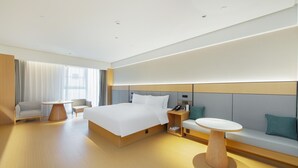 Una habitación de hotel moderna con una cama grande, una mesita de noche, una silla, un sofá y una pequeña mesa.