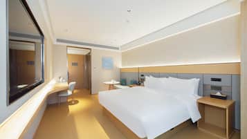 A modern hotel room with a large bed, bedside tables, a desk, and a chair.