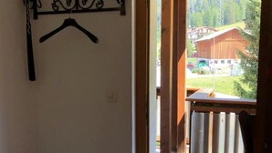 Ein Zimmer mit einer Holztür, die zu einem Außenbereich mit Blick auf einen Berg und ein Gebäude führt.
