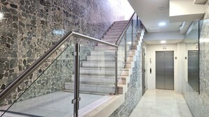Um interior moderno com parede de azulejos de pedra, escada de metal com guarda-corpo de vidro e design limpo e minimalista.
