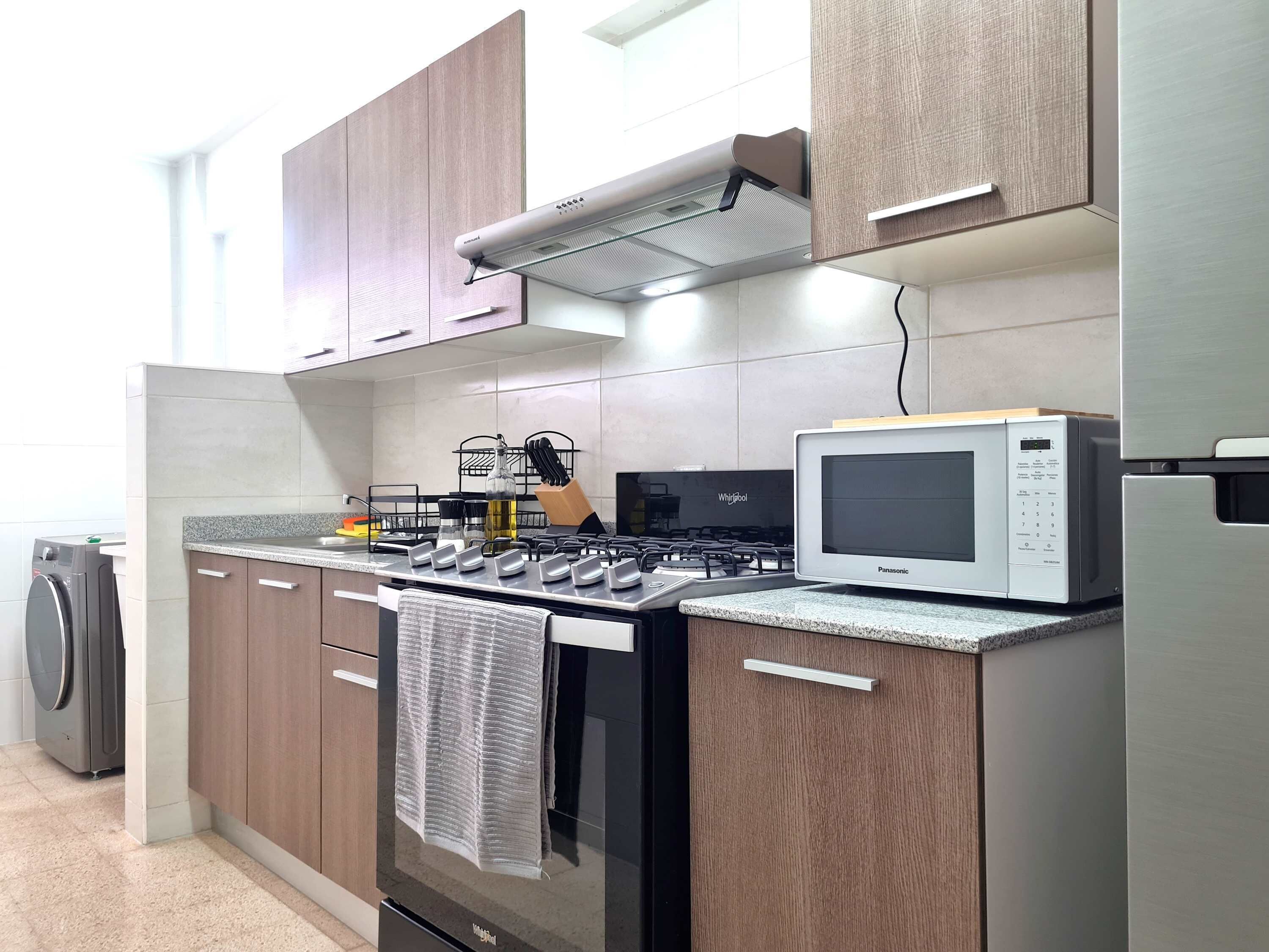 Una cocina moderna con armarios de madera, estufa a gas, microondas y horno empotrado.