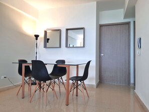 A modern dining area with a glass table, four black chairs, and two wall-mounted mirrors.