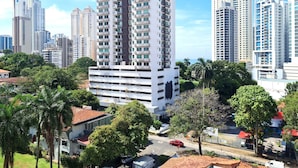 A high-rise residential building with multiple balconies, surrounded by greenery and other high-rise buildings. - w* | Unparalleled 2BR In La Cresta (Panamá)