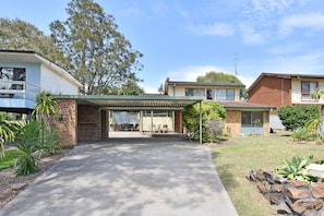 A residential property with a covered patio, a brick exterior, and a well-maintained lawn.
