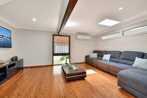Una sala de estar moderna con un sofá gris, suelo de madera, una mesa de centro y un cuadro en la pared.