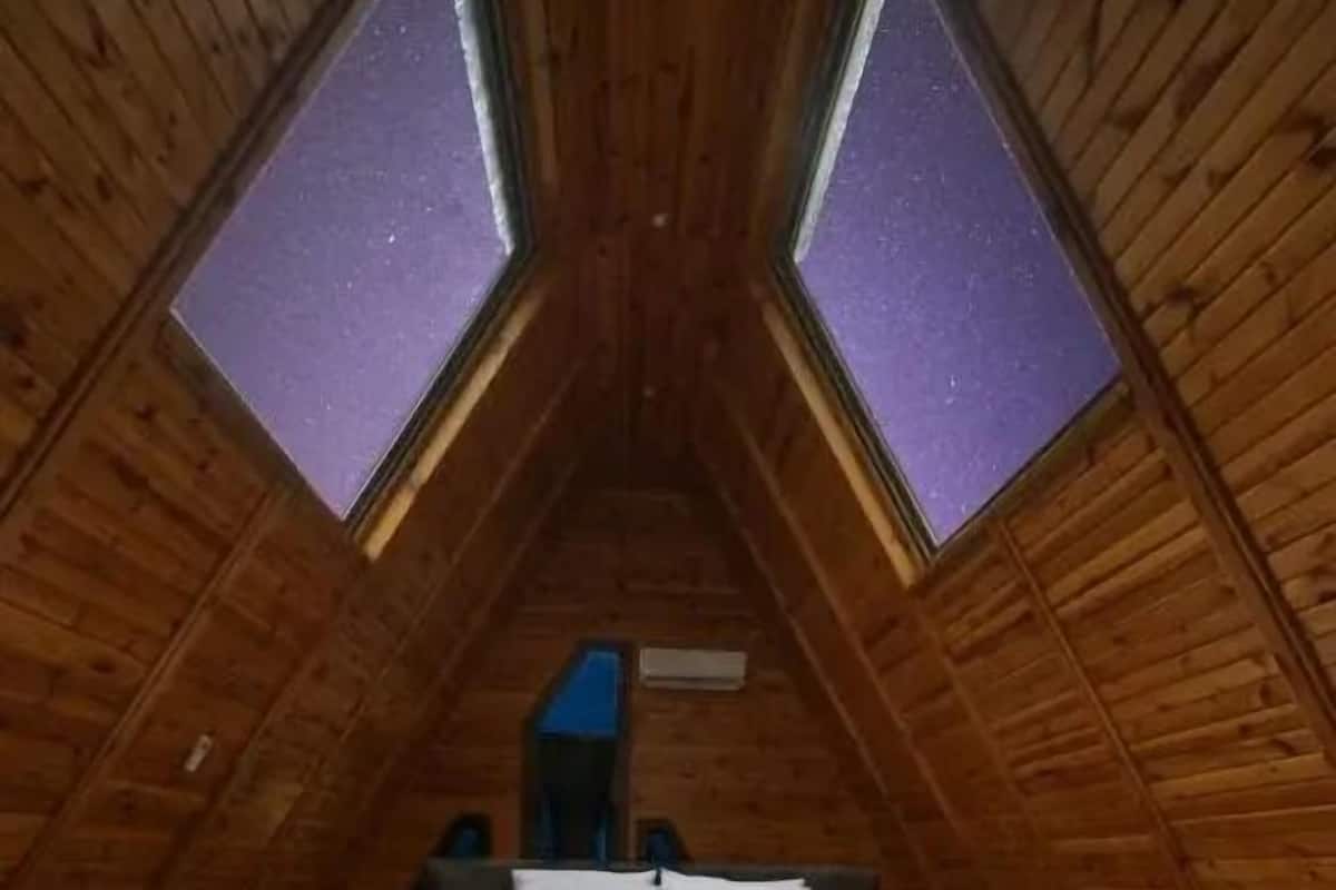 A wooden attic bedroom with a bed, a small table, and a bench.