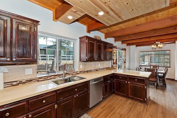 A spacious kitchen with wooden cabinets, a large island, and a dining area with a table and chairs.