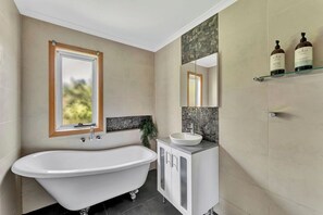 Une salle de bain avec une baignoire sur pieds, un meuble-lavabo et un miroir au-dessus du lavabo.