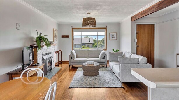 A modern living room with a fireplace, two grey sofas, a round coffee table, and a large window offering a view of the outdoors.