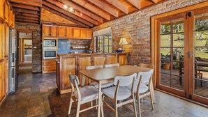 Una cocina rústica con armarios de madera, una isla central y un comedor con sillas.