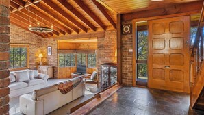 Interior acogedor de una cabaña de madera con chimenea, un sofá y un televisor.