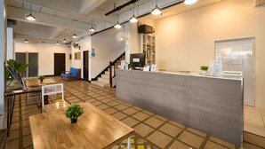A reception area with a counter, seating, and a staircase. - Thapae60 Mini Hotel (Chiang Mai)