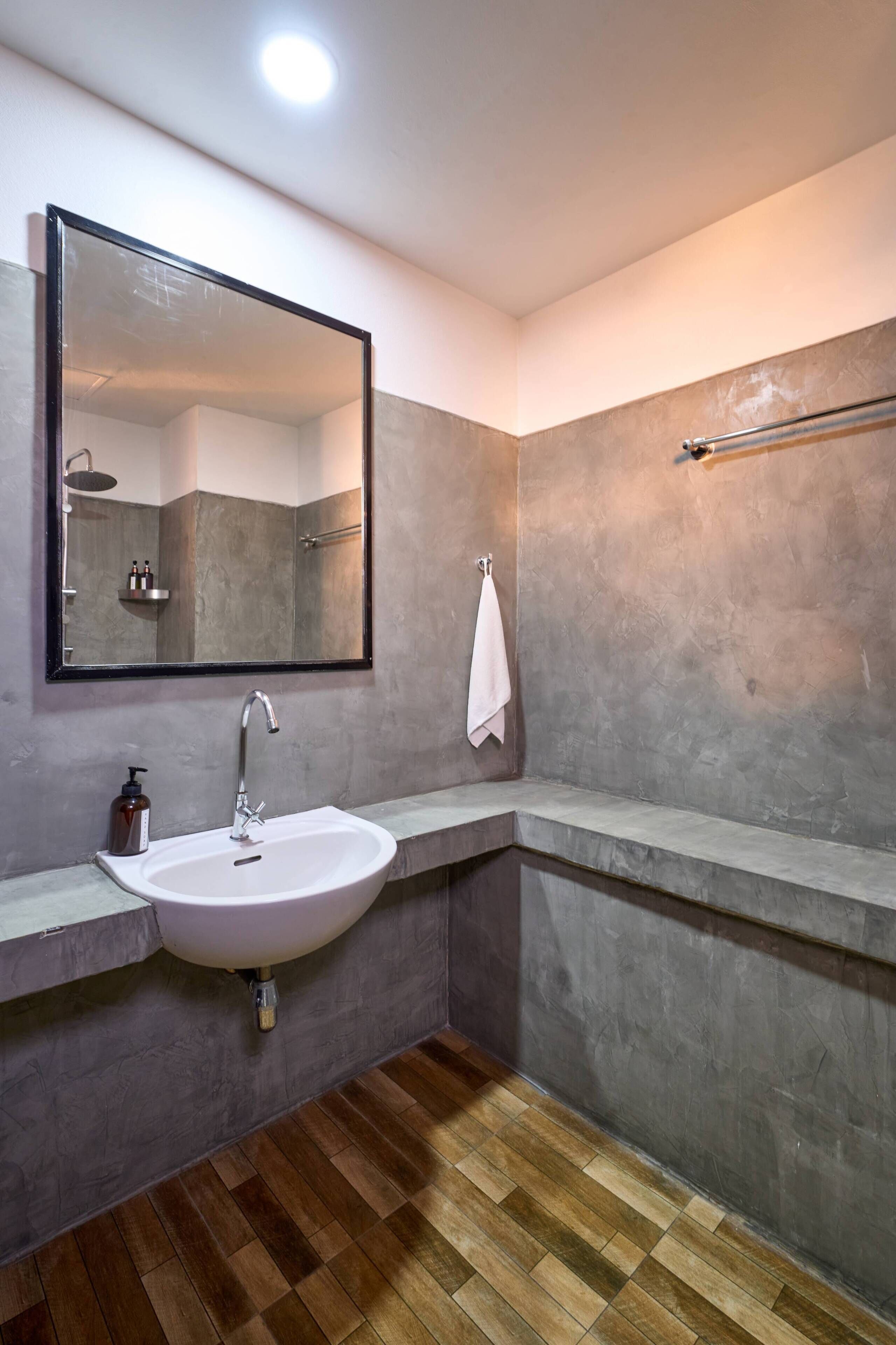 A bathroom with a large mirror, a sink, a towel rack, and a shower area.