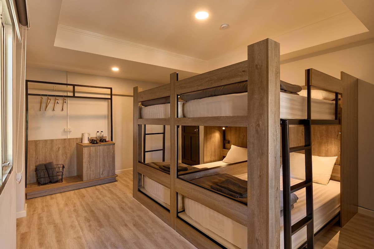 Habitación con literas, un armario de madera y una pequeña zona de estar.