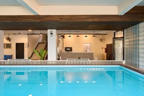 A swimming pool with a reception desk, a staircase, and a glass wall with a grid pattern. - Thapae60 Mini Hotel (Chiang Mai)