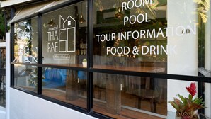 A window with text advertising room pool, tour information, food & drink, and a mini hotel. - Thapae60 Mini Hotel (Chiang Mai)