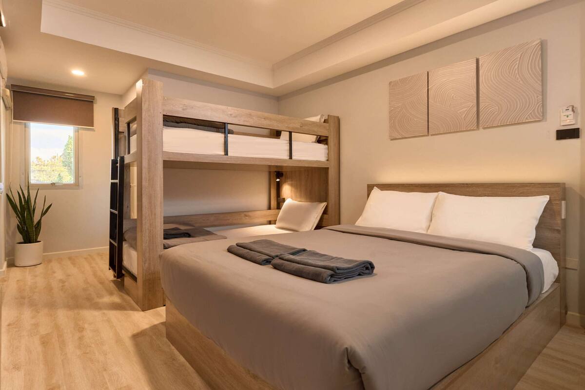 Un dormitorio moderno con una cama nido, una cama grande y una planta en maceta.
