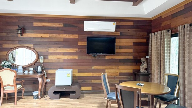 A room with wooden panel walls, a flat-screen TV, a wooden dining table with chairs, a small white heater, and a mirror.