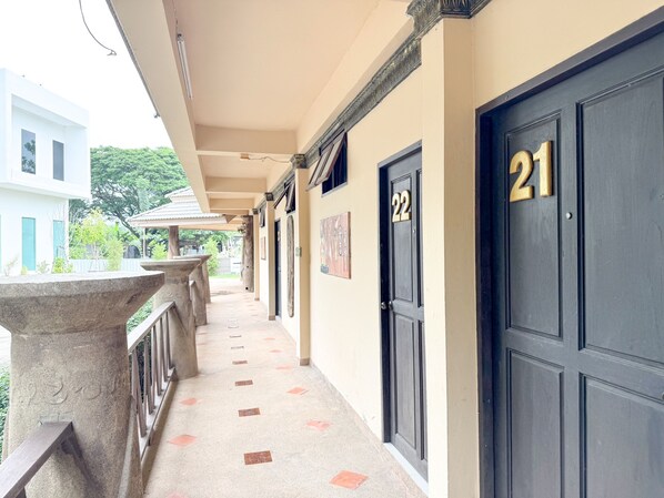 A corridor with numbered doors, a stone balustrade, and a tiled floor.