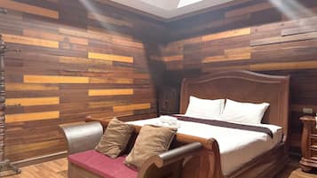 Una habitación con una cama de madera, un banco con cojines y una pared de madera con tablones horizontales.