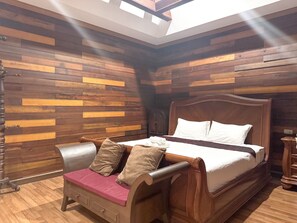 Una habitación con una cama de madera, un banco con cojines y una pared de madera con tablones horizontales.