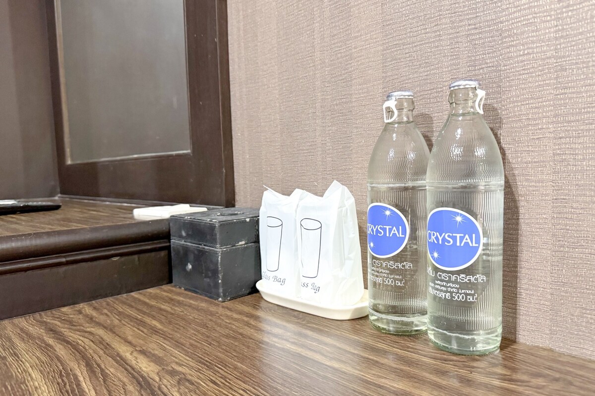 A wooden table with two bottles of Crystal water, a black box, and a white tissue box.