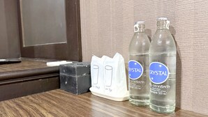 A wooden table with two bottles of Crystal water, a black box, and a white tissue box.
