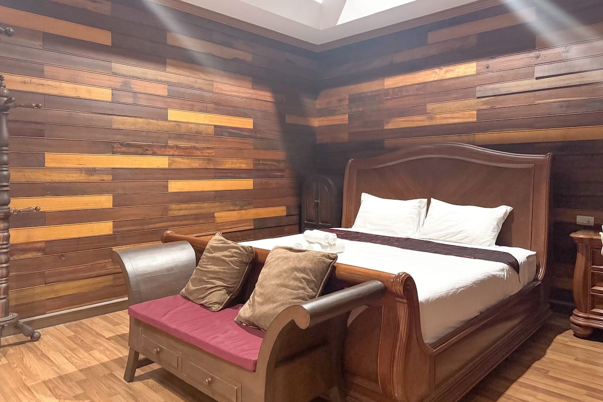 A room with a wooden bed, a bench with cushions, and a wooden wall with horizontal planks.