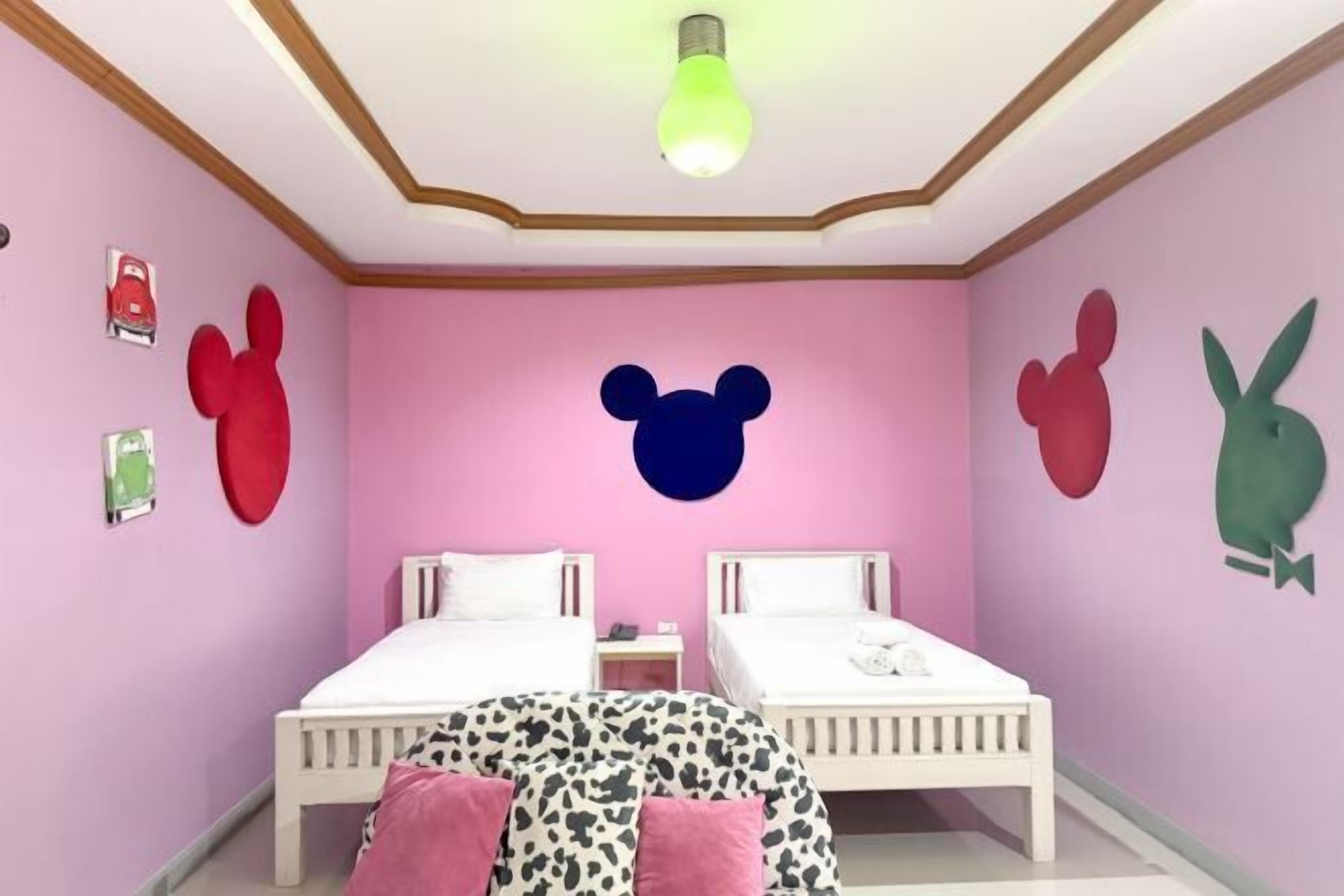 Habitació amb dos llits, una làmpada al sostre i decoracions murals.