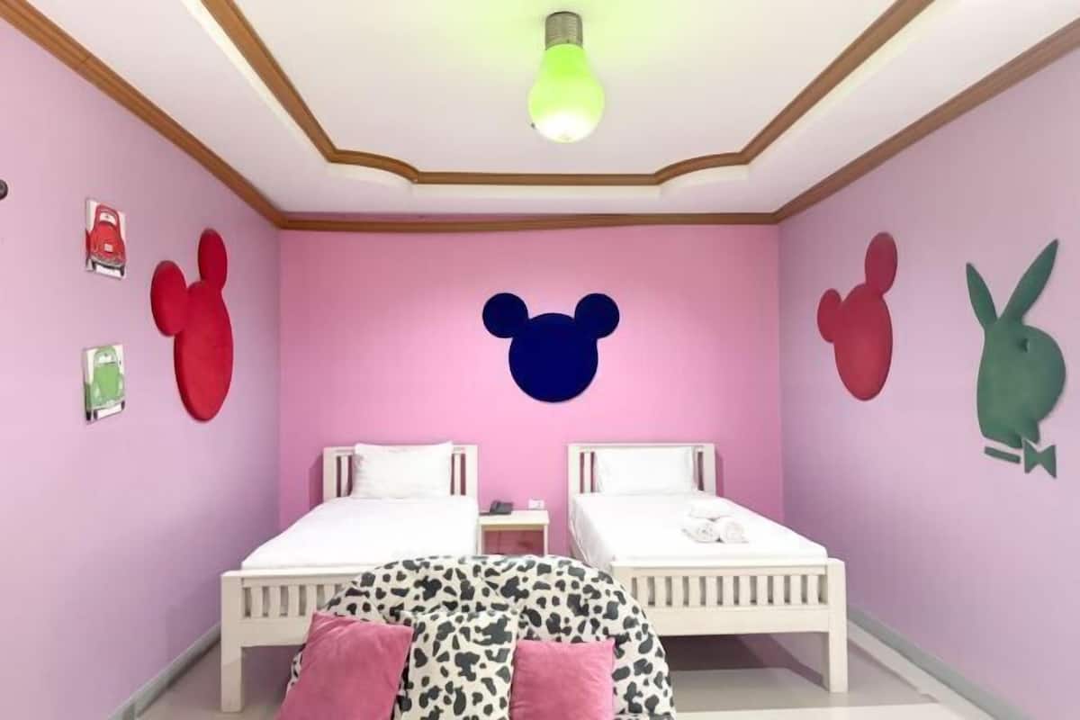 A room with two beds, a ceiling light, and wall decorations.