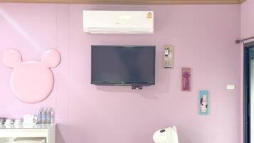 Una habitación con pared rosa, televisor montado, aire acondicionado y refrigerador blanco.