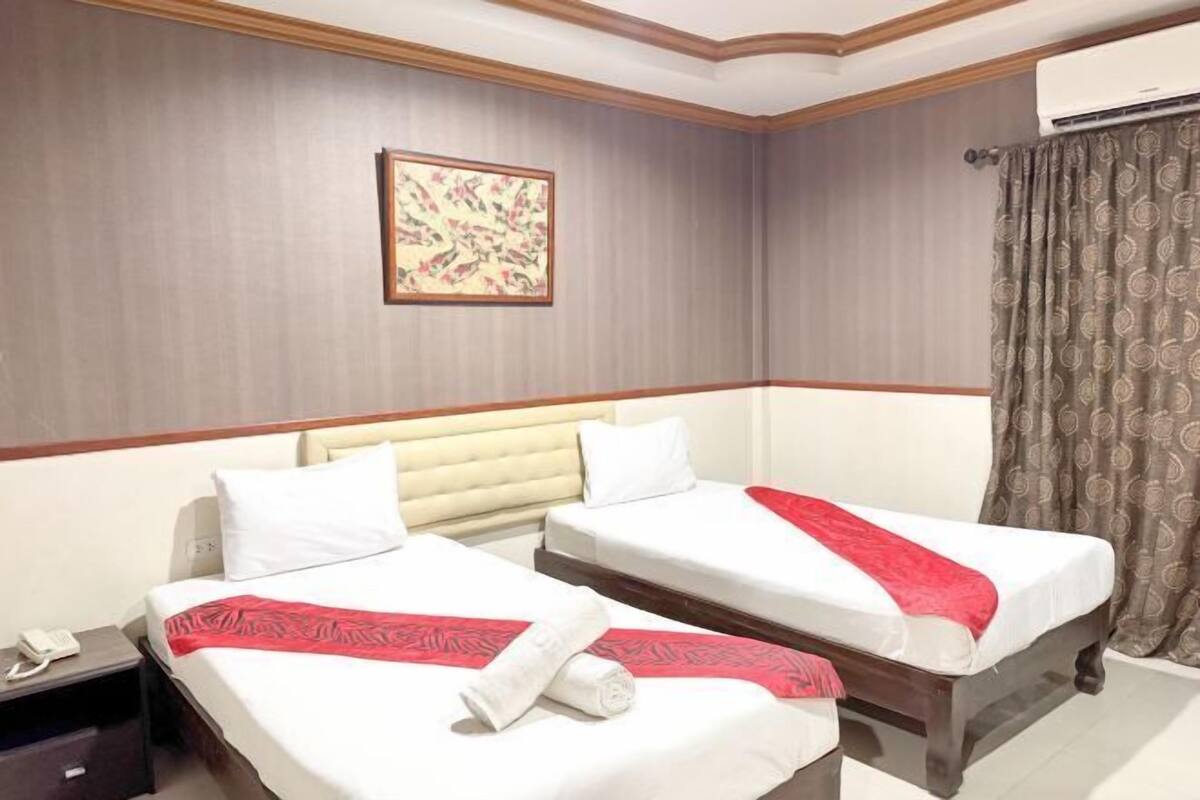 A hotel room with two beds, a telephone, and a framed picture on the wall.