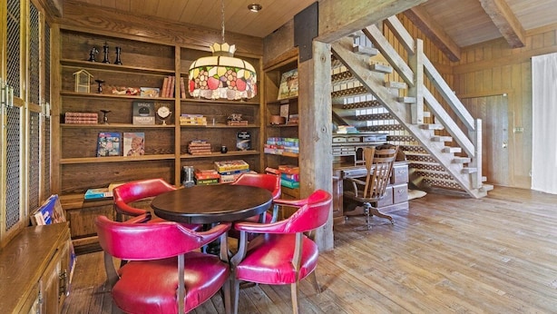 A wooden interior with a staircase, bookshelves, and a round table with chairs. - Landing(43M0)- Sleeps 20 + Airway Strip + Hot Tub (Pleasant Hill)