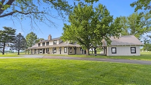 A large, single-story building with a covered porch and a separate white building attached to it. - Landing(43M0)- Sleeps 20 + Airway Strip + Hot Tub (Pleasant Hill)